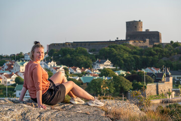 Smiling Caucasian Woman sunlit Enjoying Sunset over Swedish Summer party Island and Village Marstrand, Near Gothenburg and Sweden West Coast.