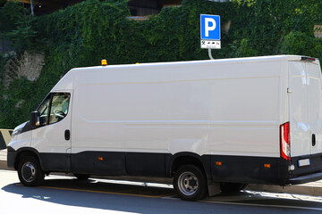 White van with top emergency orange light parked along a road. Parking sign for unloading goods...