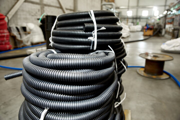 Large coils of black corrugated pipe at the factory