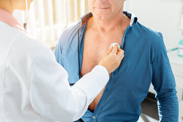 Doctor checking lung function of male patient with stethoscope