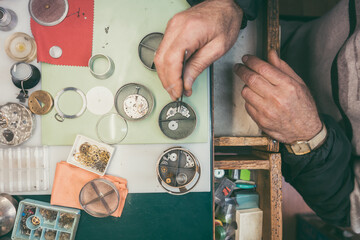 Hands of experienced watchmaker fixing a watch in close-up