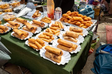  Set of Crispy spring rolls on white paper dish, sell on stall at Thai Park, open air market, in Berlin, Germany. Asian street food. © Peeradontax