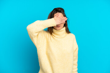 Young caucasian woman isolated on blue background covering eyes by hands. Do not want to see...