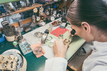 Watchmaker woman absorbed in her delicate work wearing spectacles