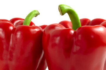Two red peppers with green stalks close up.
