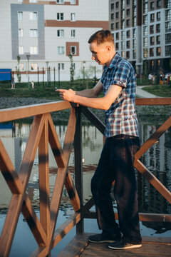 A young man is working on a photo shoot c in a checkered shirt with short sleeves.

