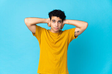 Fototapeta na wymiar Young Venezuelan man isolated on blue background frustrated and covering ears