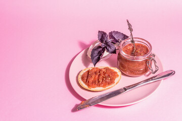 Chutney from rhubarb. Delicious food, traditional seasonal sauce on pastel pink background