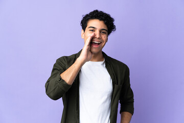 Young Venezuelan man isolated on purple background shouting with mouth wide open