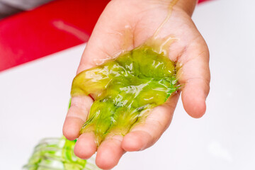 Child playing with red color slime, gunge, gel in hands