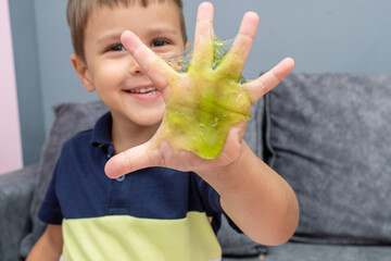 Child playing with red color slime, gunge, gel in hands