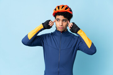 Venezuelan cyclist man isolated on blue background having doubts and thinking
