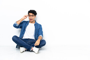 Venezuelan man sitting on the floor with glasses and surprised