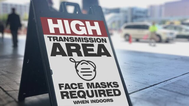 A sign on the sidewalk at a convention center warns people that this is a "high transmission" area for COVID-19. The CDC again required face masks when the delta variant surged in 2021 in certain area