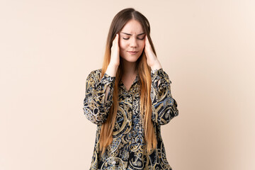 Young caucasian woman isolated on beige background with headache