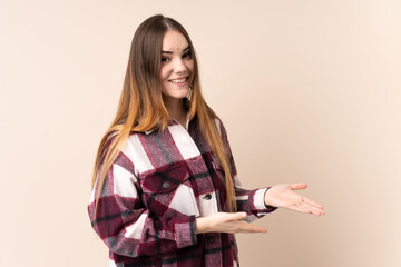 Young caucasian woman isolated on beige background extending hands to the side for inviting to come