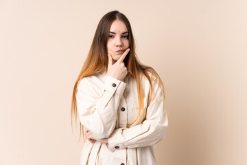 Young caucasian woman isolated on beige background thinking