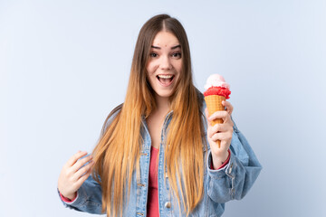 Young woman with a cornet ice cream isolated on blue background with surprise and shocked facial...