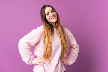 Young caucasian woman isolated on purple background posing with arms at hip and smiling