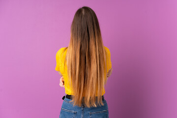 Young caucasian woman isolated on purple background in back position