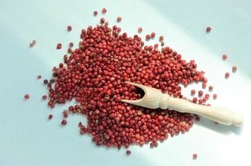red pepper peas on a white background with glare from the light, a wooden spoon lies on the pepper