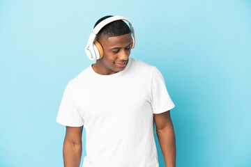 Young latin man isolated on blue background listening music