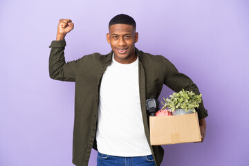 Latin man making a move while picking up a box full of things doing strong gesture
