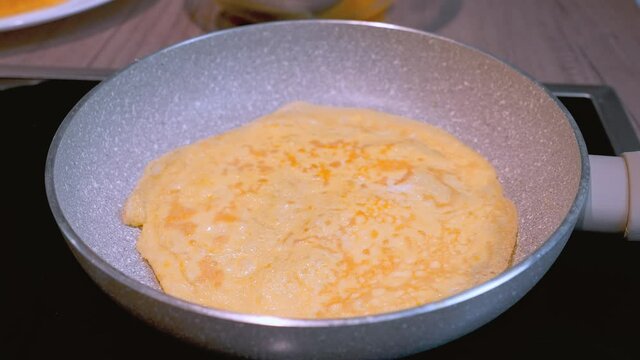 Omelette making process. Woman flips the aggs to the other side. close up