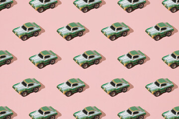 Old metal sport car toy green color on pink background. Minimal design. Pattern.