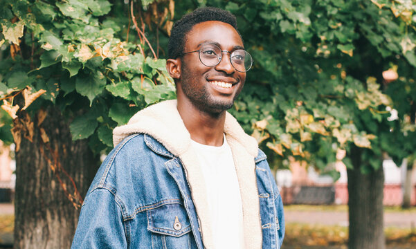 Portrait of happy smiling african man looking away wearing an eyeglasses in autumn city park