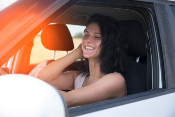 A smiling young woman enjoying driving on a beautiful sunny day