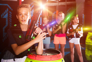 Portrait of happy teenager boy with laser pistol posing in laser tag labyrinth..