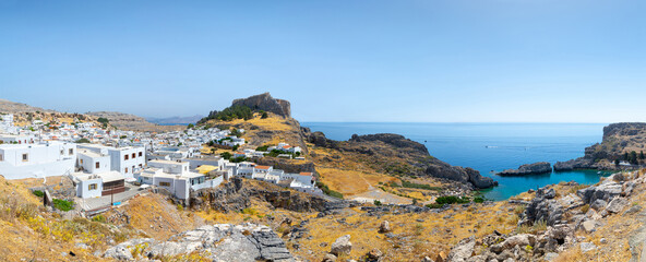 Obraz premium Lindos, with its ancient acropolis, ruins fortress and closed bays in sea coast, is the most view place of Rhodes island in Dodecanese, Greece. Vacation on Greece islands in Mediterranean sea.