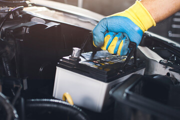 Fototapeta Technician is pulling up an car old battery for replacement obraz