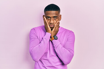 Young black man wearing casual pink sweater tired hands covering face, depression and sadness, upset and irritated for problem