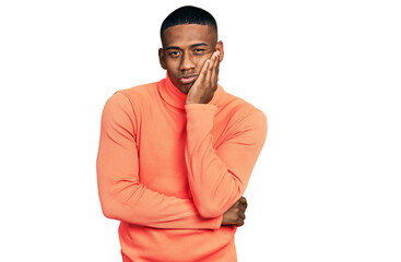 Young black man wearing orange turtleneck sweater thinking looking tired and bored with depression problems with crossed arms.