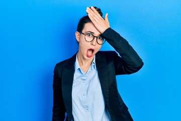 Young hispanic girl wearing business clothes and glasses surprised with hand on head for mistake, remember error. forgot, bad memory concept.