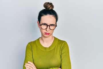 Young hispanic girl wearing casual clothes and glasses skeptic and nervous, disapproving expression on face with crossed arms. negative person.