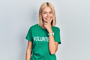 Beautiful blonde woman wearing volunteer t shirt looking confident at the camera smiling with...