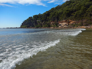 wave breaking at the beach with mountain in background