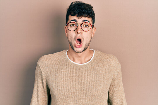 Young hispanic man wearing casual clothes and glasses afraid and shocked with surprise and amazed expression, fear and excited face.