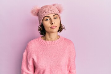 Young brunette woman wearing cute wool cap relaxed with serious expression on face. simple and natural looking at the camera.