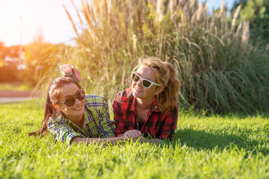 two young pretty teenager girls best friends laying on grass at sunny summer day