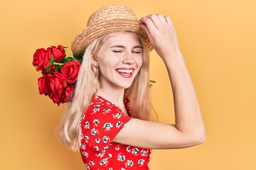 Beautiful caucasian woman with blond hair holding bouquet of red roses smiling and laughing hard out loud because funny crazy joke.
