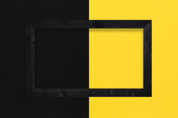Black photo frame placed on yellow and black paper background.