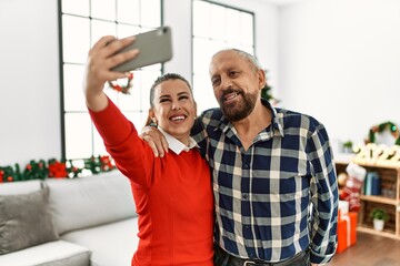 Young daughter and senior father together celebrating christmas at home taking selfie picture