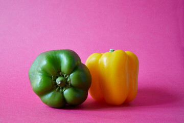 Sweet pepper. Green and yellow bell pepper on fuchsia background.