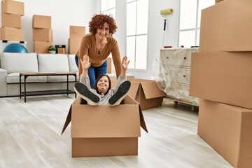 Fototapeta premium Mature mother and down syndrome daughter moving to a new home, having fun inside box