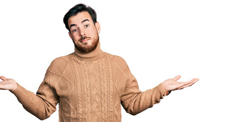 Young hispanic man wearing casual clothes clueless and confused expression with arms and hands raised. doubt concept.