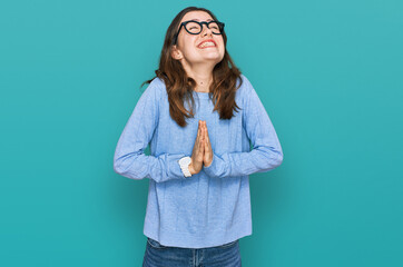 Young beautiful woman wearing casual clothes and glasses begging and praying with hands together...